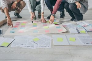 cropped view of scrum masters pointing with fingers at sticky notes on floor