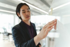 Successful Asian businessman planning startup using flip chart sticky notes, selective focus on hand